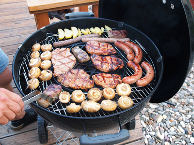 Voll bestückter Gas Kugelgrill mit Fleisch, Wurst und Gemüse